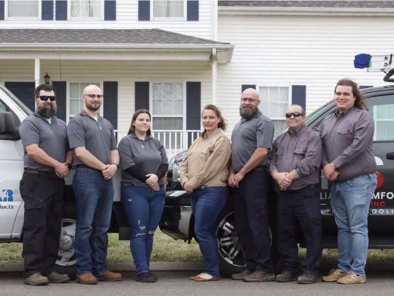 The Reliable Comfort Services team standing together in front of their service vans outside a Murfreesboro home