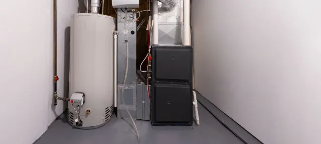 A Reliable Comfort Services technician inspects a residential furnace during a maintenance visit, checking the heat exchanger and safety controls.