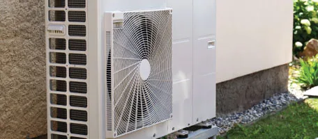 A compact ductless mini-split unit tucks neatly against the side of a home, delivering efficient, room-by-room comfort.