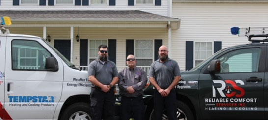 The Reliable Comfort Services team standing together in front of their service vans at a Murfreesboro home